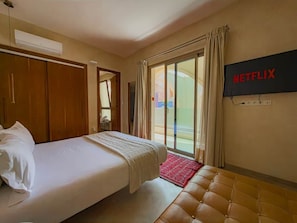 A hotel room with a bed, a television mounted on the wall, and a sliding glass door to the outside. - The Red Room at Riad Timija: En-suite, Breakfast & Rooftop in the Medina (Marrakesh)