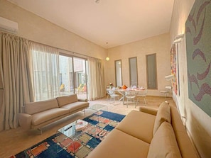 A modern living room with a sofa, a coffee table, and a dining area with a table and chairs. - The Red Room at Riad Timija: En-suite, Breakfast & Rooftop in the Medina (Marrakesh)