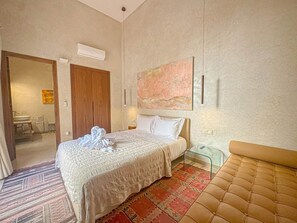 A hotel room with a bed, a bedside table, a chair, a window, and a bathroom visible through an open door. - The Green Room at Riad Timija: En-suite, Breakfast & Rooftop in the Medina (Marrakesh)
