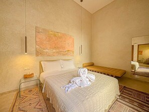 A hotel room with a large bed, a smaller sofa, a bedside table, a mirror, and a painting on the wall. - The Green Room at Riad Timija: En-suite, Breakfast & Rooftop in the Medina (Marrakesh)