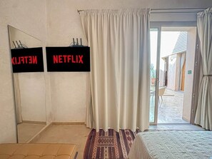 A hotel room with a bed, a door leading to a balcony, and a wall-mounted sign indicating the room's name. - The Green Room at Riad Timija: En-suite, Breakfast & Rooftop in the Medina (Marrakesh)
