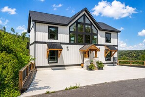 Ett modernt hus i två våningar med en stor veranda på framsidan, ett garage och en rymlig uppfart.