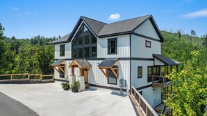 A two-story building with a large balcony and a covered porch area. - Gatlinburg Getaway with Hot Tub, Mountain Views, Theater, Game Room & Smoky Mountains (Gatlinburg)