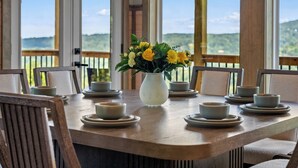 A dining table with a vase of yellow flowers, surrounded by chairs and plates. - Gatlinburg Getaway with Hot Tub, Mountain Views, Theater, Game Room & Smoky Mountains (Gatlinburg)