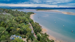 Luftaufnahme einer Küstenlandschaft mit Strand, Booten und dichter Vegetation.
