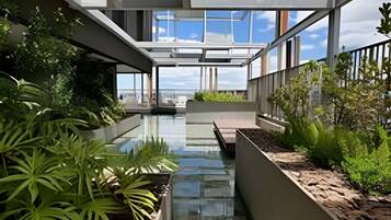 A modern building with a glass atrium, water feature, and greenery.