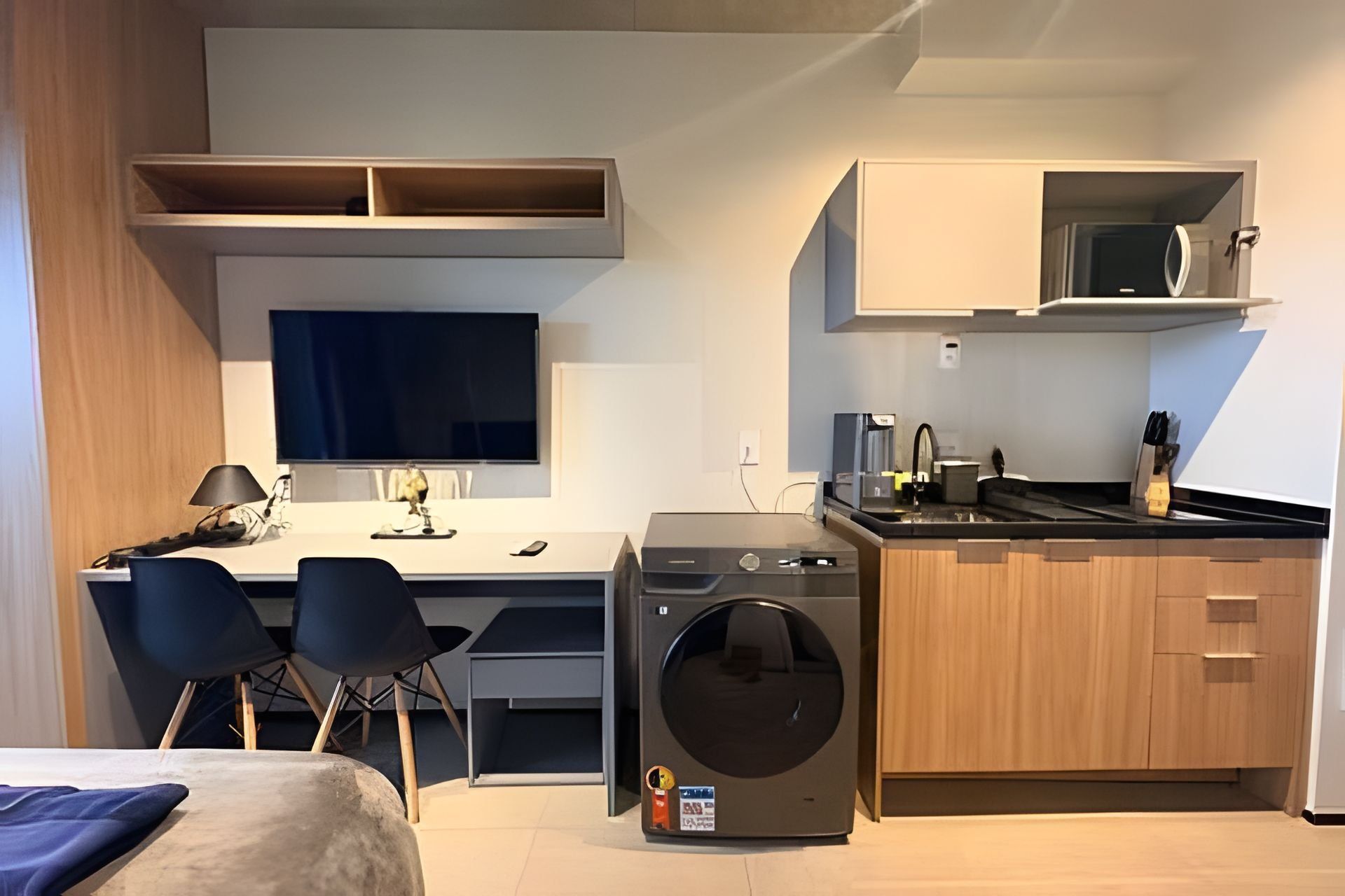 A compact kitchenette with a microwave, sink, and a washing machine.
