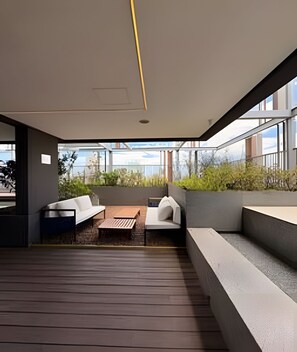 Un espacio al aire libre moderno con suelo de madera, pared de piedra y vistas a la ciudad.