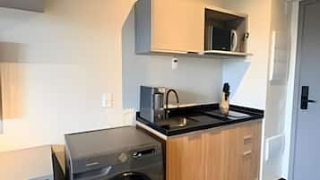 A compact kitchen with a built-in washing machine, a microwave, and a sink.