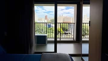 Una habitación de hotel con una cama, una ventana con vistas a un balcón y una puerta.