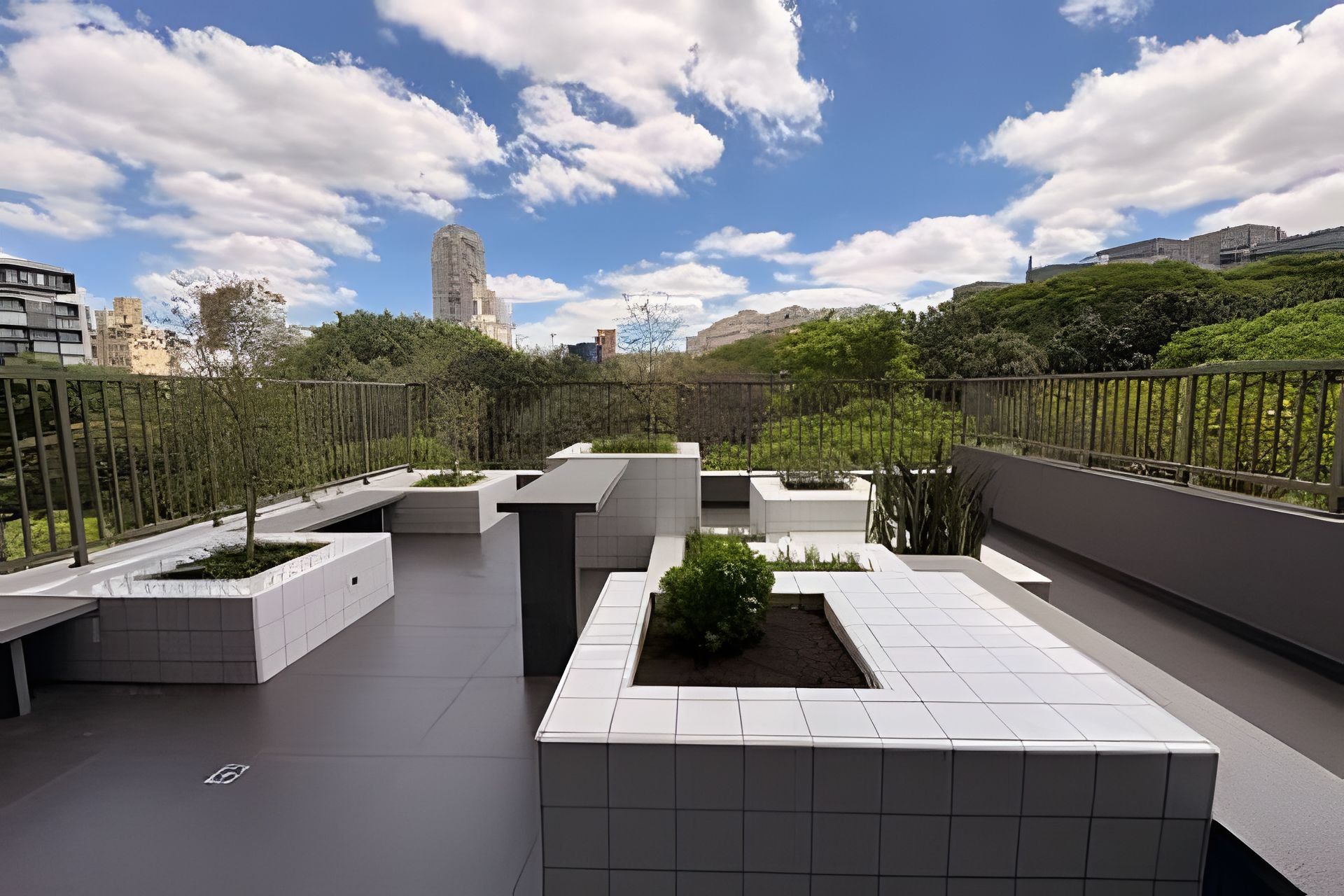 Terraço no telhado com design moderno, apresentando vasos geométricos e vista desobstruída do horizonte da cidade.