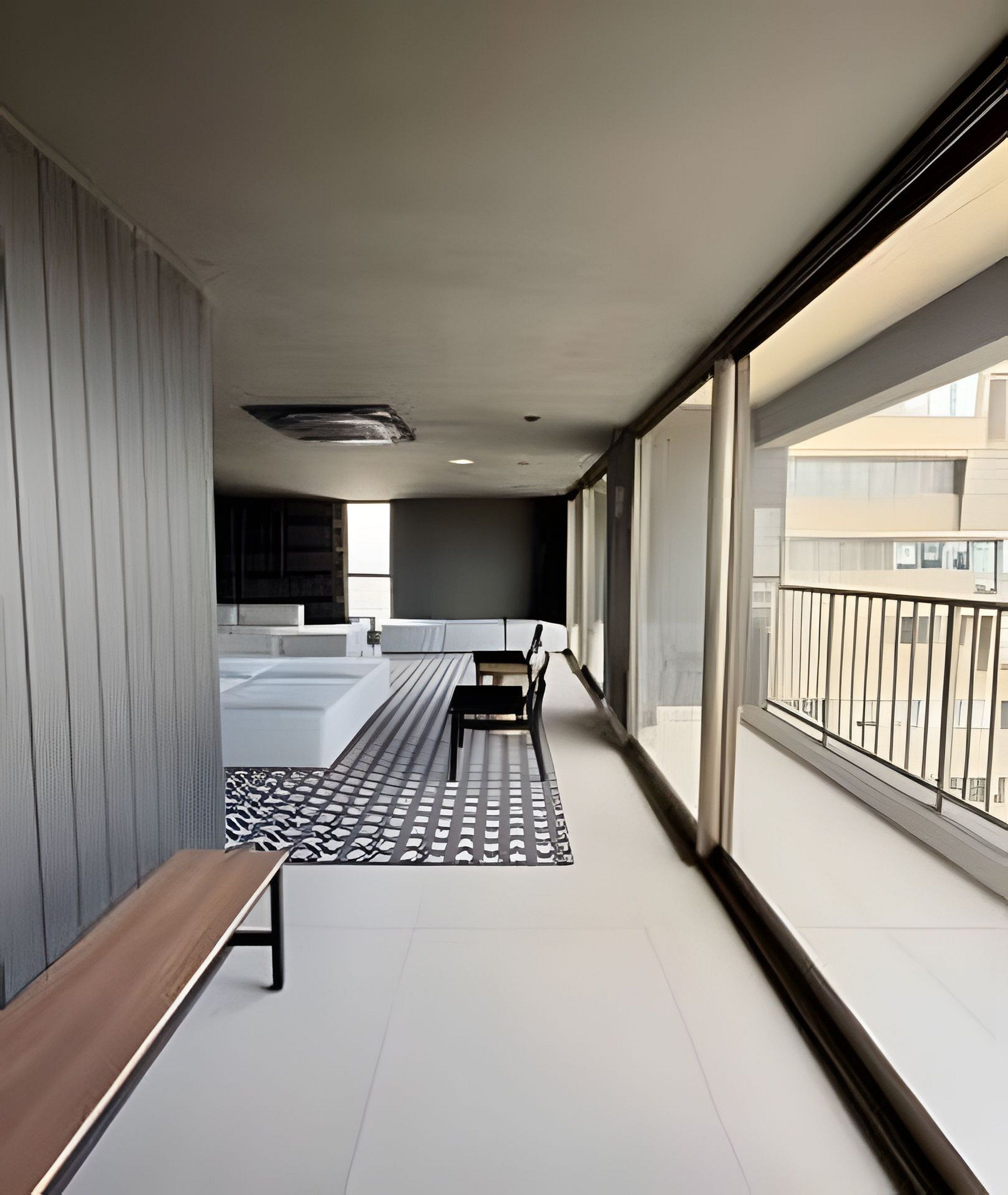A modern balcony with a bench, a patterned rug, and a view of the cityscape.