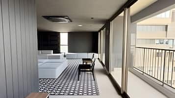 A modern balcony with a bench, a patterned rug, and a view of the cityscape.