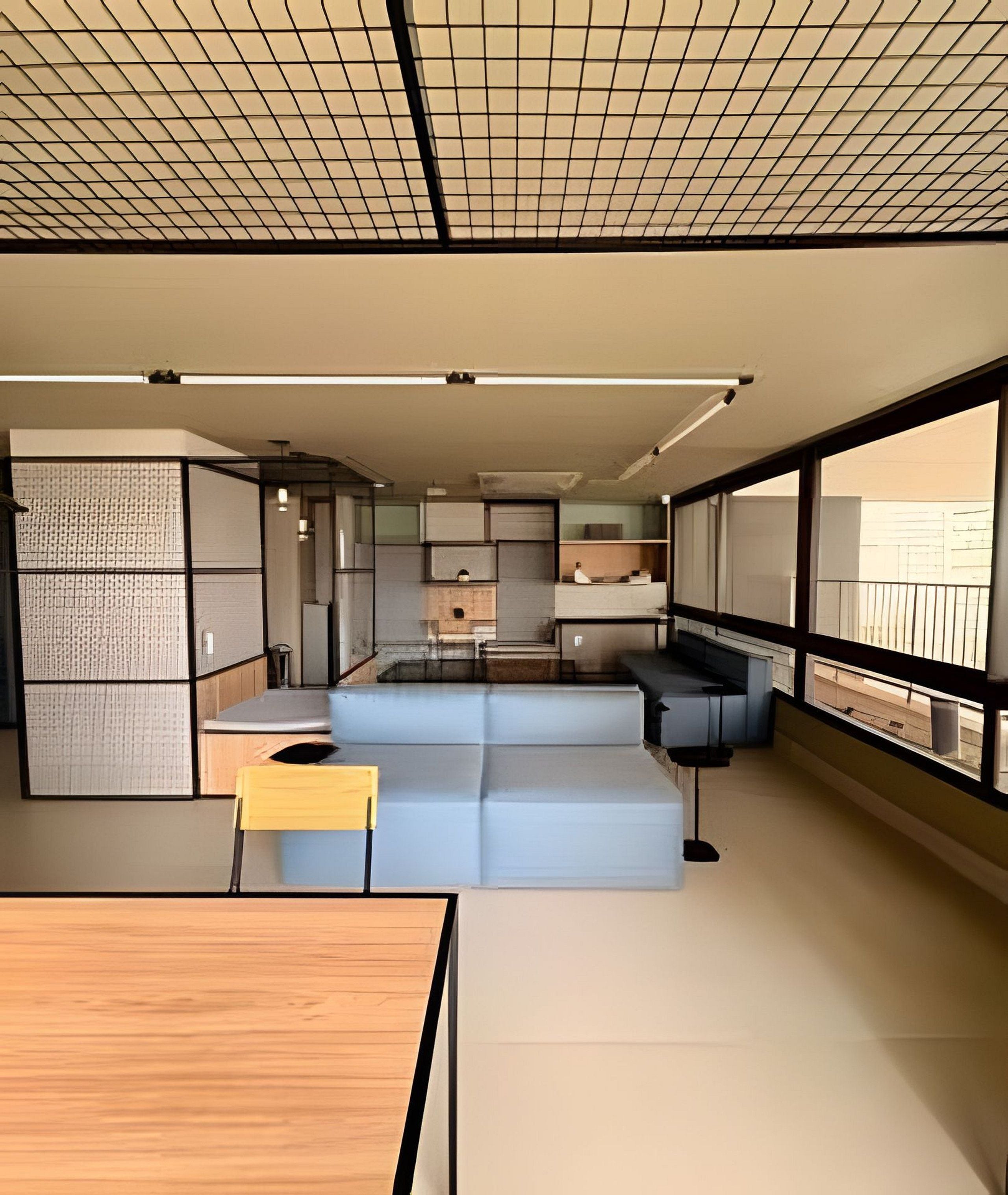 Interior moderno com área de cozinha, assentos e grandes janelas.