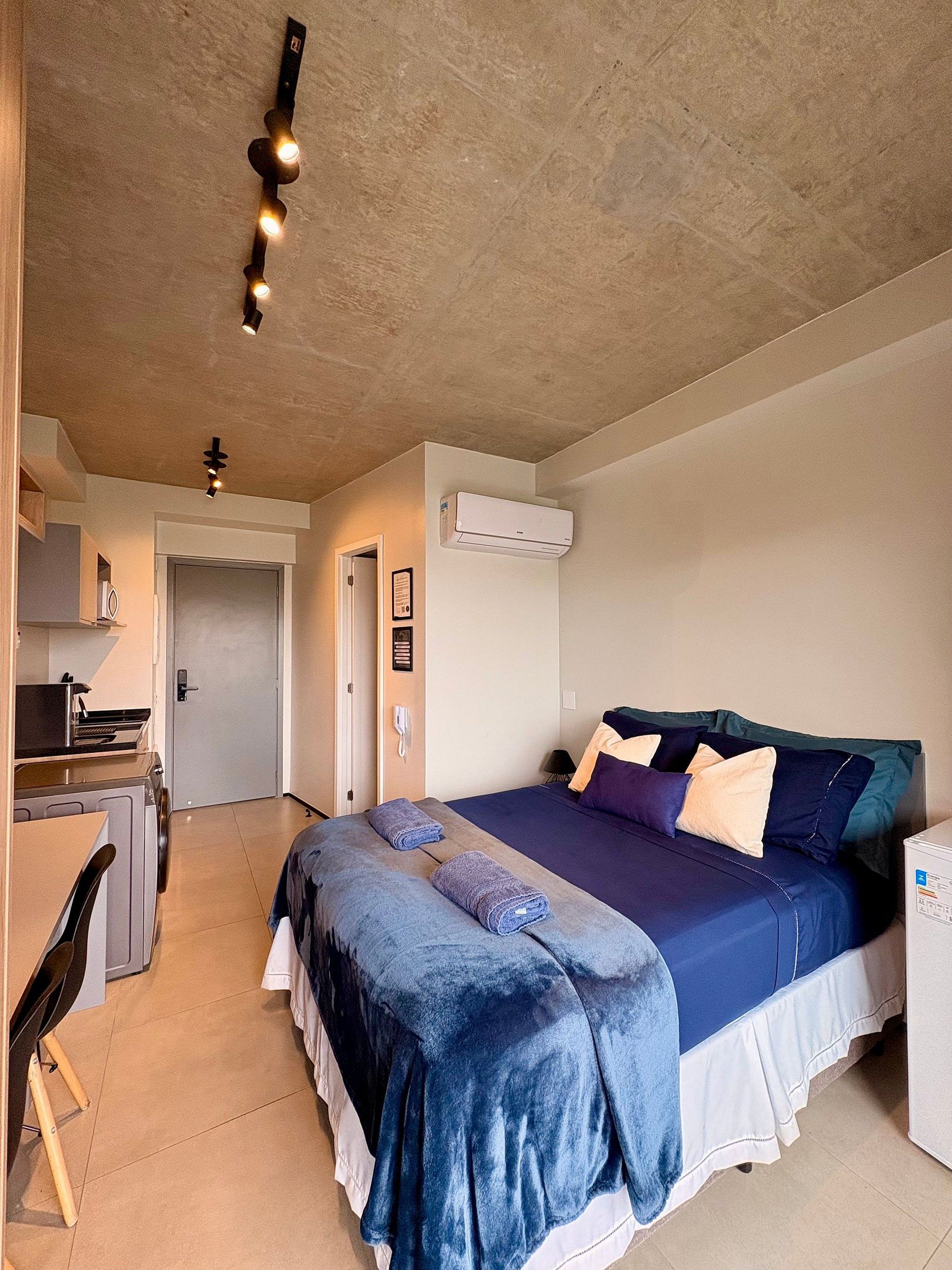 Quarto com cama, escrivaninha e ar condicionado.