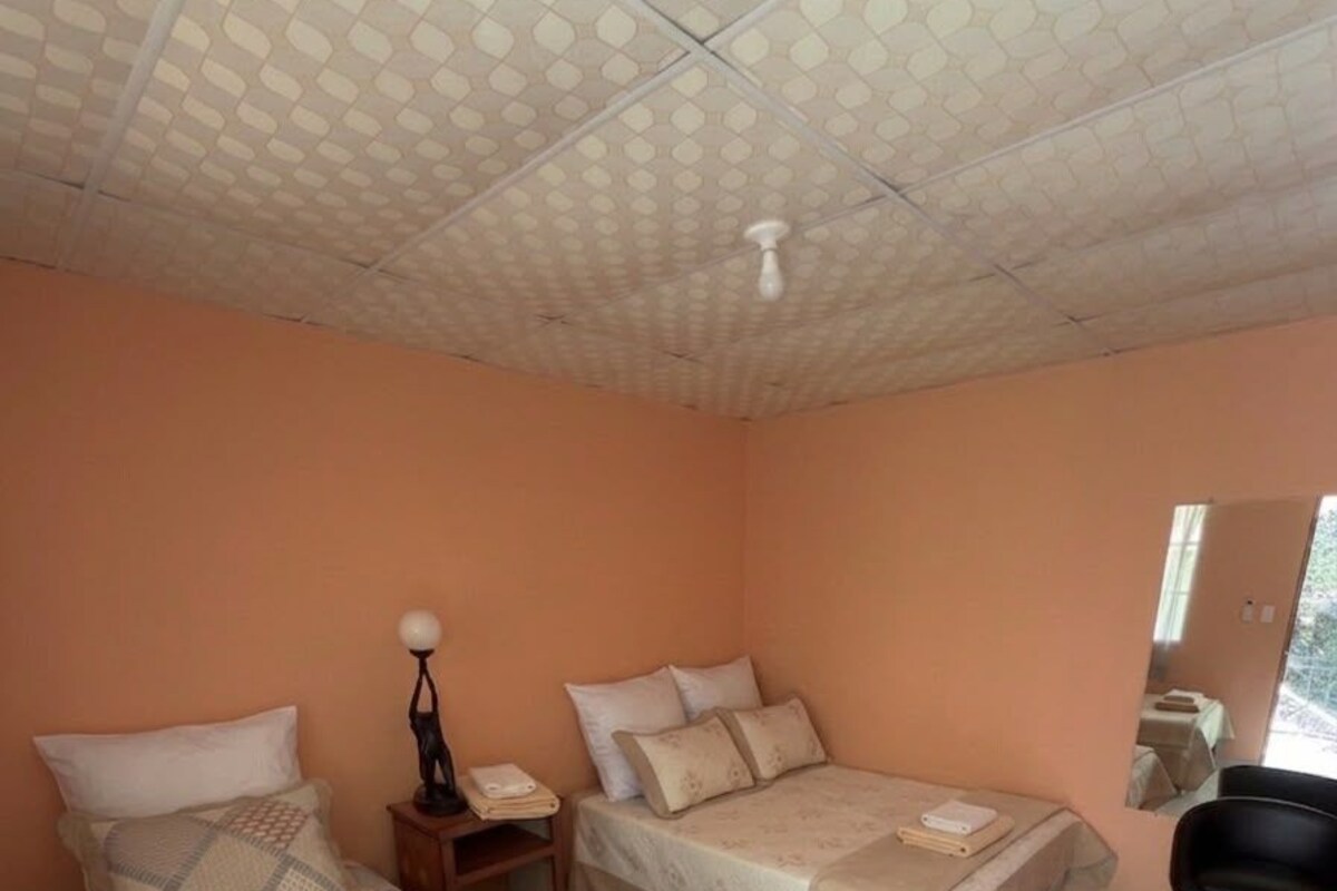 A room with two beds, a nightstand, a chair, and a ceiling with a unique pattern.