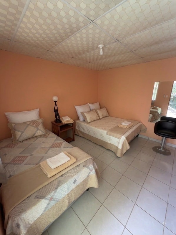 A room with two beds, a nightstand, a chair, and a ceiling with a unique pattern.