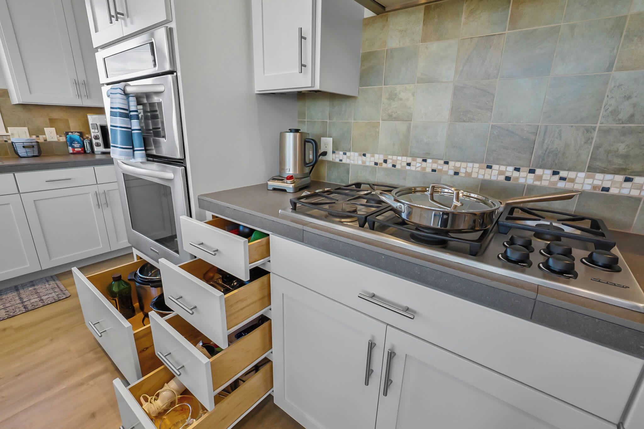 A modern kitchen with white cabinetry, a gas stove, and a tiled backsplash.