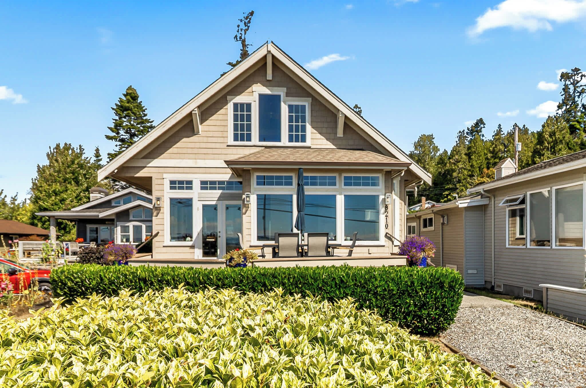 A two-story house with a large front porch, a garage, and a well-maintained garden.