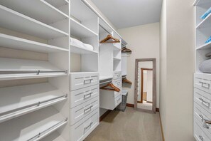 A walk-in closet with multiple shelves, drawers, and hanging space.