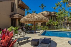 A poolside area with lounge chairs, a thatched umbrella, and a pool. - Upgraded 1BD/1.5BA ocean view condo steps away from fantastic Kam 1 beach (kihei)