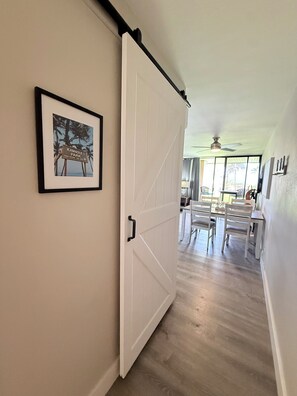 Un couloir avec une porte blanche, une enseigne encadrée et un coin repas comprenant des chaises et une table.