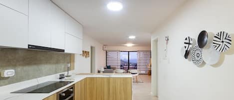 Una cocina moderna con horno empotrado, una encimera y una isla de madera. Se ve un comedor con una mesa y sillas al fondo.