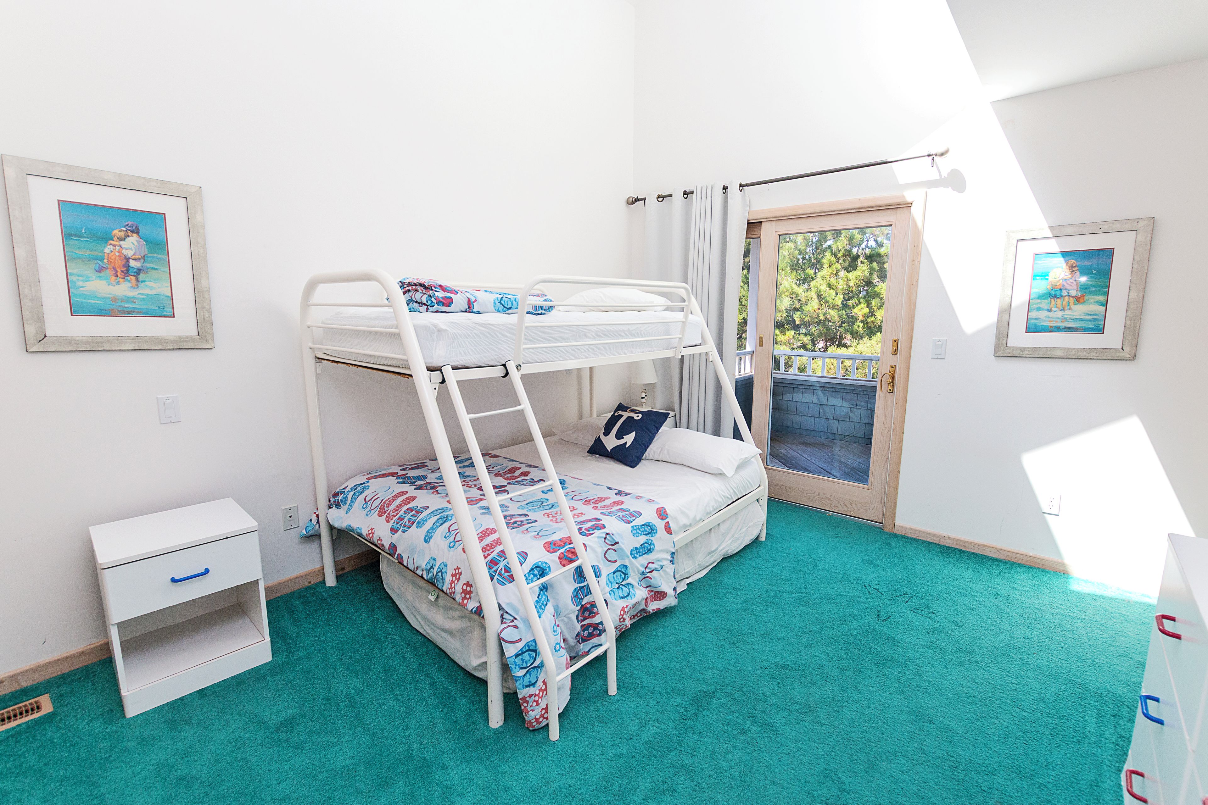 Habitació amb lliteres, una taula de nit petita i una porta que dóna a una zona exterior.