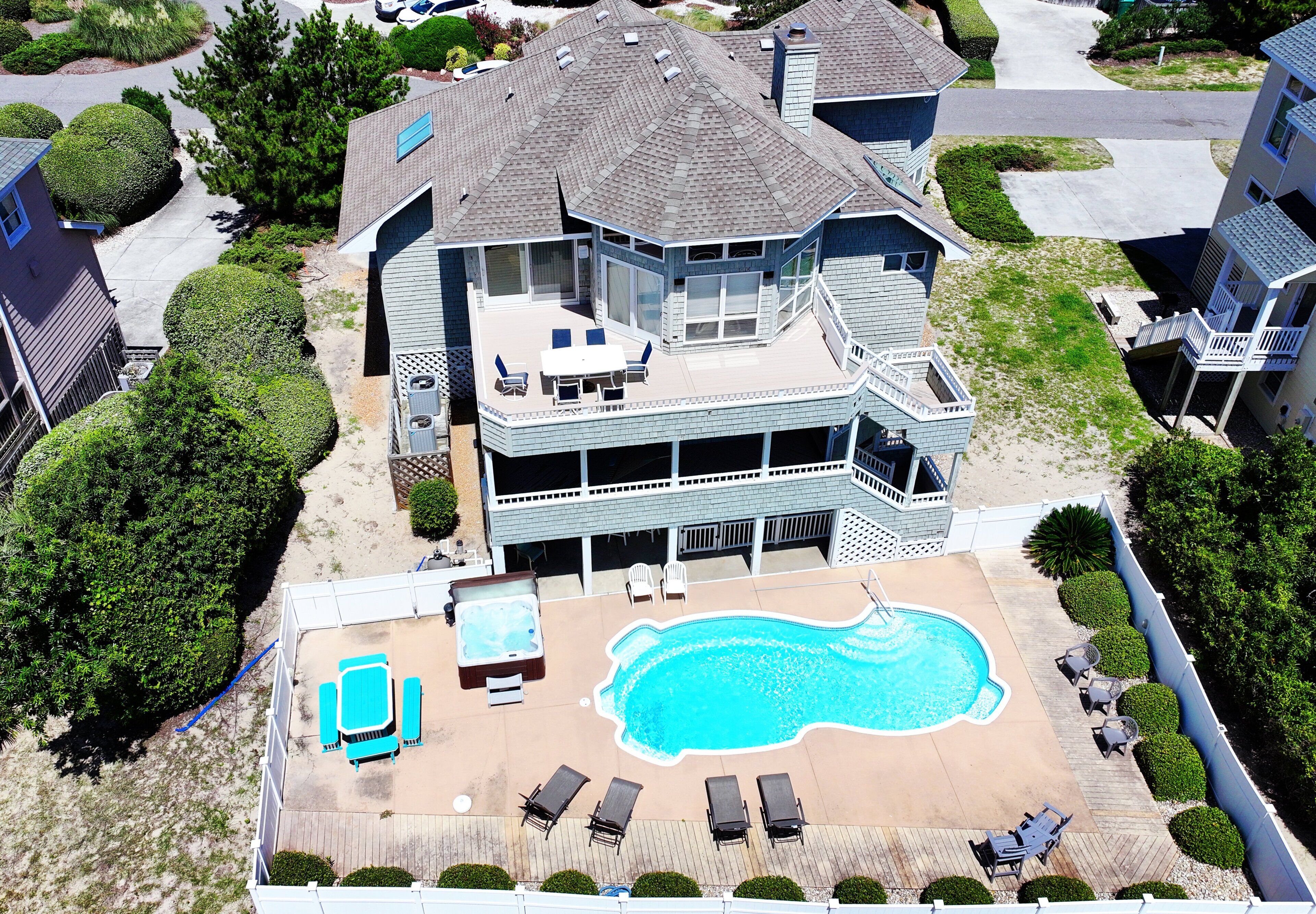 A two-story house with a large deck, a swimming pool, and a hot tub.