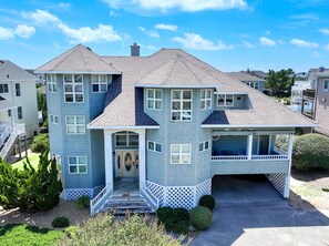 A two-story house with a front porch, a garage, and a small front yard. - Oceanside-Priv Pool, Htub, Resort Access -133, I SEA the Light (Corolla)