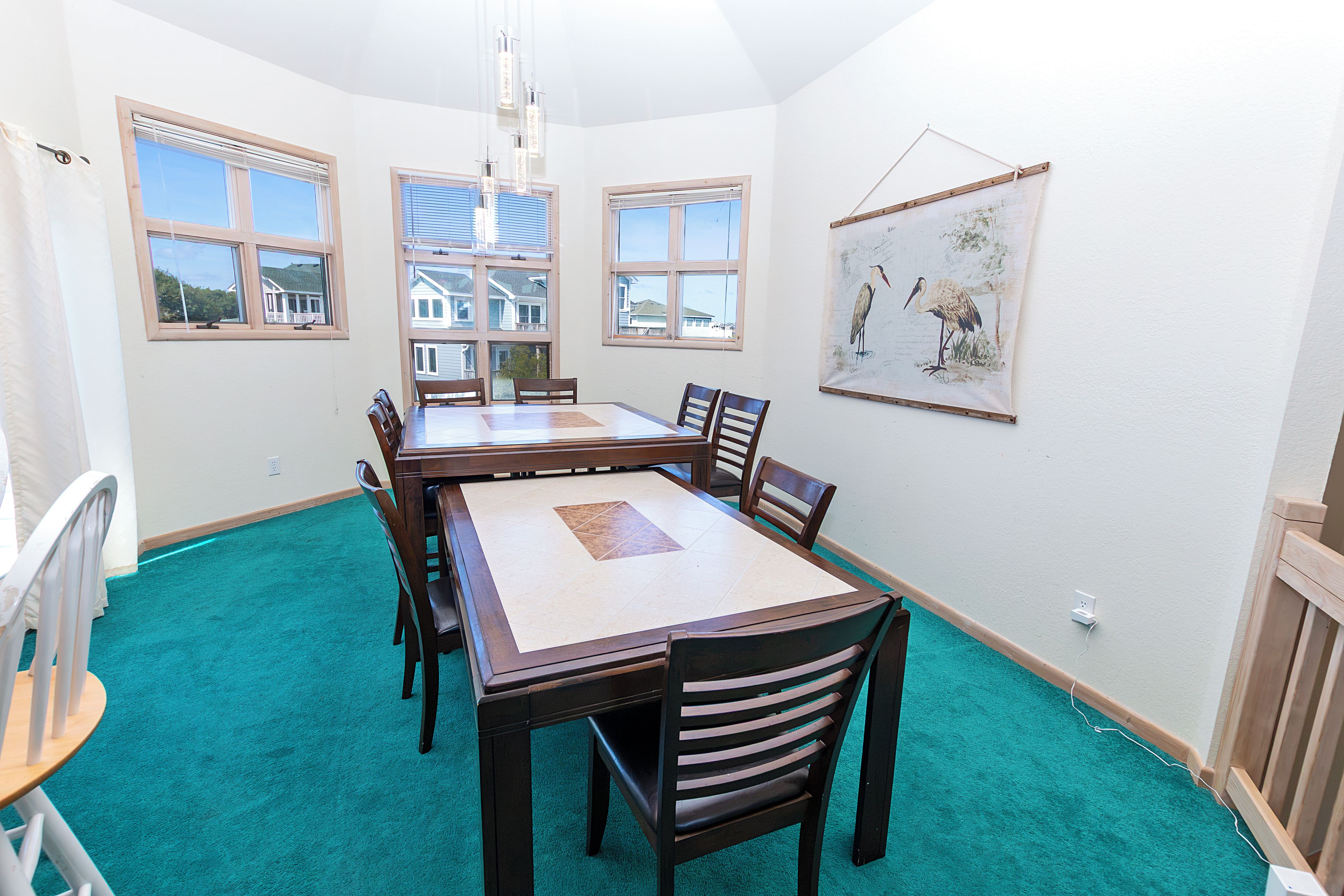 A dining room with a large table, chairs, and a painting on the wall.