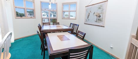 A dining room with a large table, chairs, and a painting on the wall.
