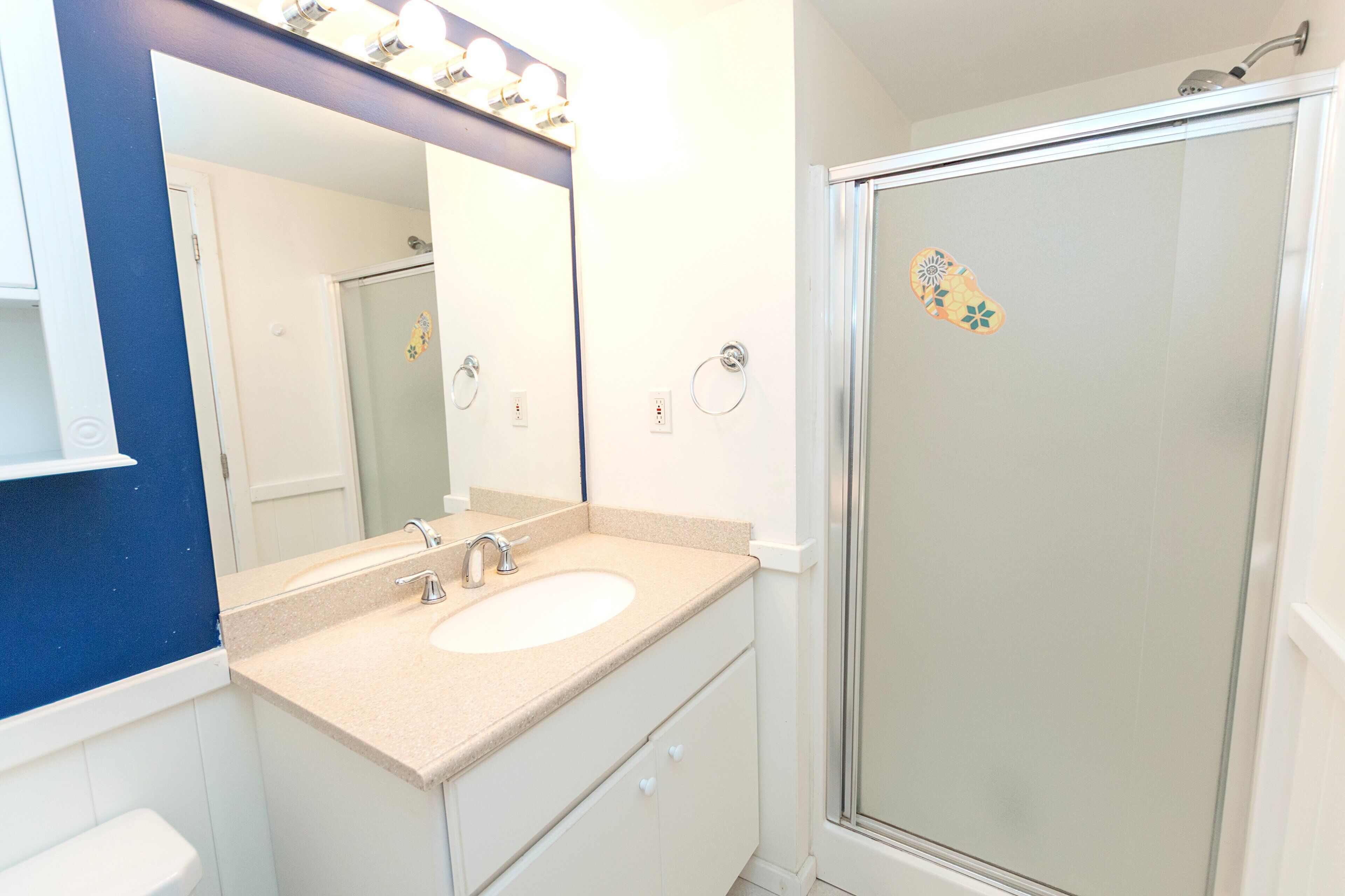 A bathroom with a sink, mirror, and shower.