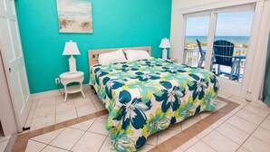 A bedroom with a bed, two bedside tables, a window with a view of the beach, and a door. - OCEANFRONT, Ocean views, Dogs Welcome, Hot Tub- CP24, ROAR by the Shore (Corolla)