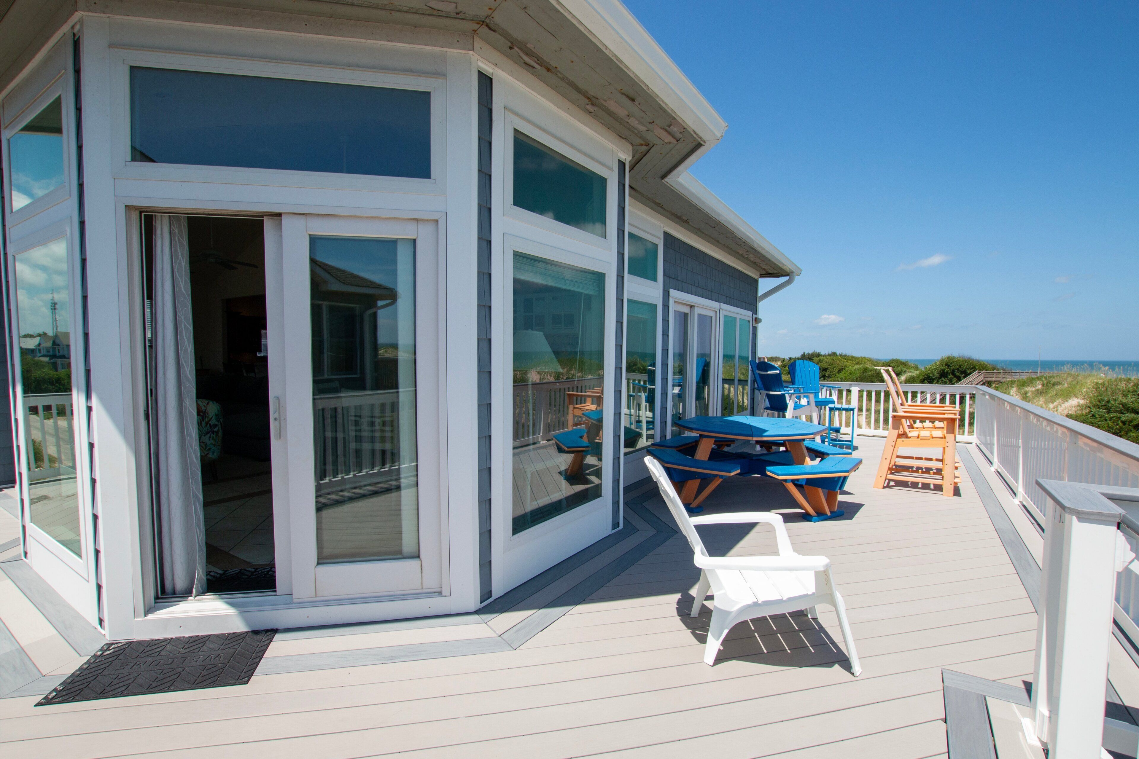 A covered outdoor area with a deck, a glass door entrance, and outdoor seating.