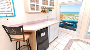 A kitchen with a view of the beach, a bar stool, a sink, and a refrigerator. - OCEANFRONT, Ocean views, Dogs Welcome, Hot Tub- CP24, ROAR by the Shore (Corolla)