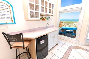 Eine Küche mit Meerblick, ein Barhocker, ein Spülbecken und ein Kühlschrank.