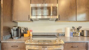 Eine Küche mit Edelstahlgeräten, darunter eine Mikrowelle, ein Backofen und eine Kaffeemaschine.