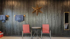 Ein Zimmer mit zwei roten Stühlen, einem kleinen runden Tisch, einer Holzstern-Dekoration und einem gefliesten Boden.