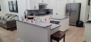 A modern kitchen with white cabinetry, a marble countertop, and a stainless steel refrigerator. - Serene 3-bedroom house plus office with AC in Fort Worth (Fort Worth)
