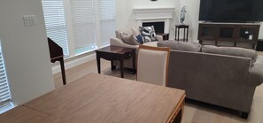 A living room with a sofa, a coffee table, a fireplace, and a television. - Serene 3-bedroom house plus office with AC in Fort Worth (Fort Worth)