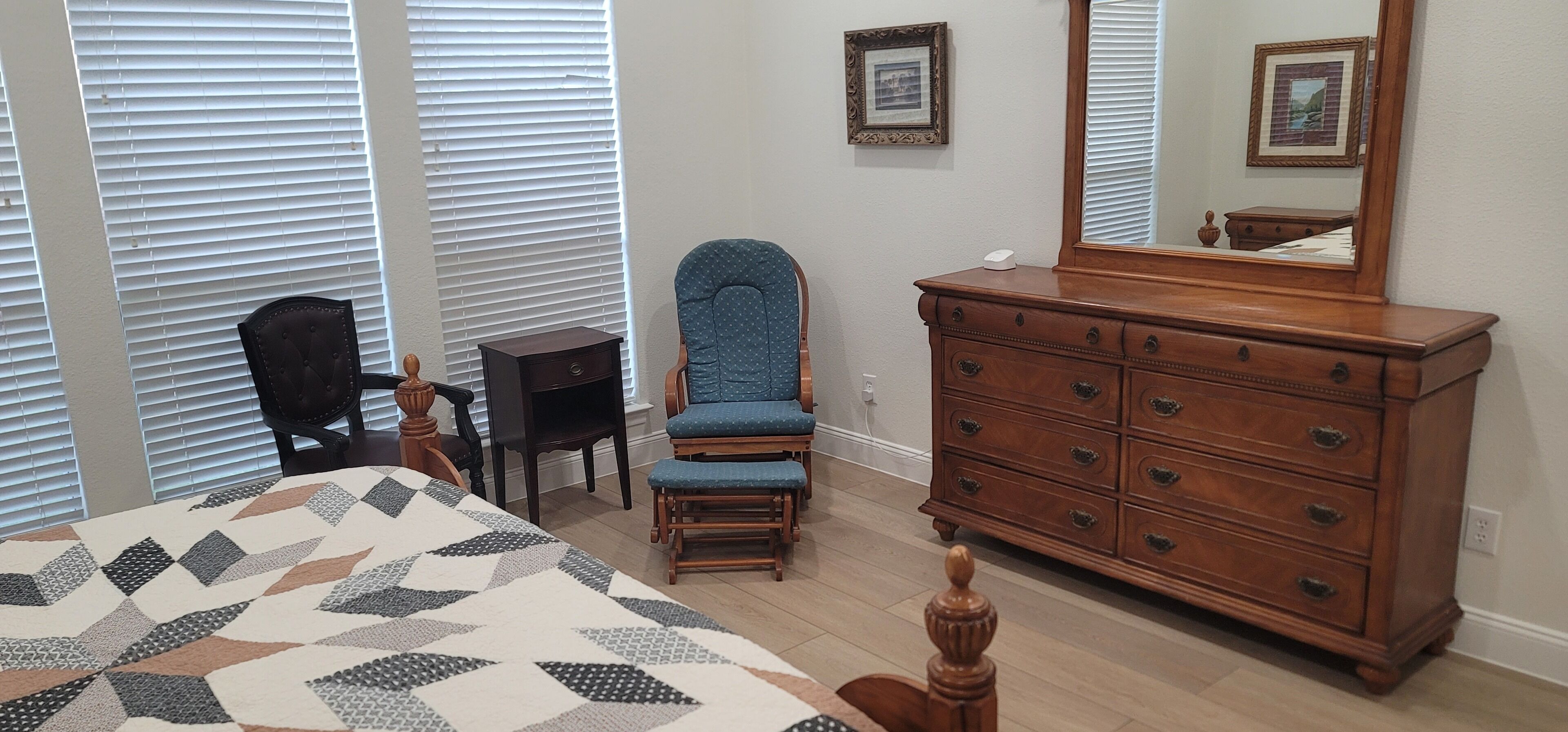 A bedroom with a bed, dresser, chair, and a large mirror.