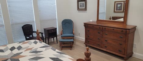 A bedroom with a bed, dresser, chair, and a large mirror.