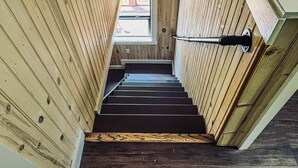A wooden interior with a staircase leading to a window.
