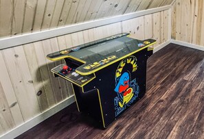 Ein kleiner Spielautomat mit farbenfrohem Design, platziert in einer Ecke mit Holzwänden und -böden.