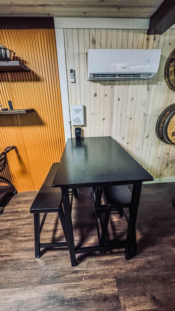 A wooden-paneled room with a table and bench, an air conditioning unit, and a wall-mounted phone.