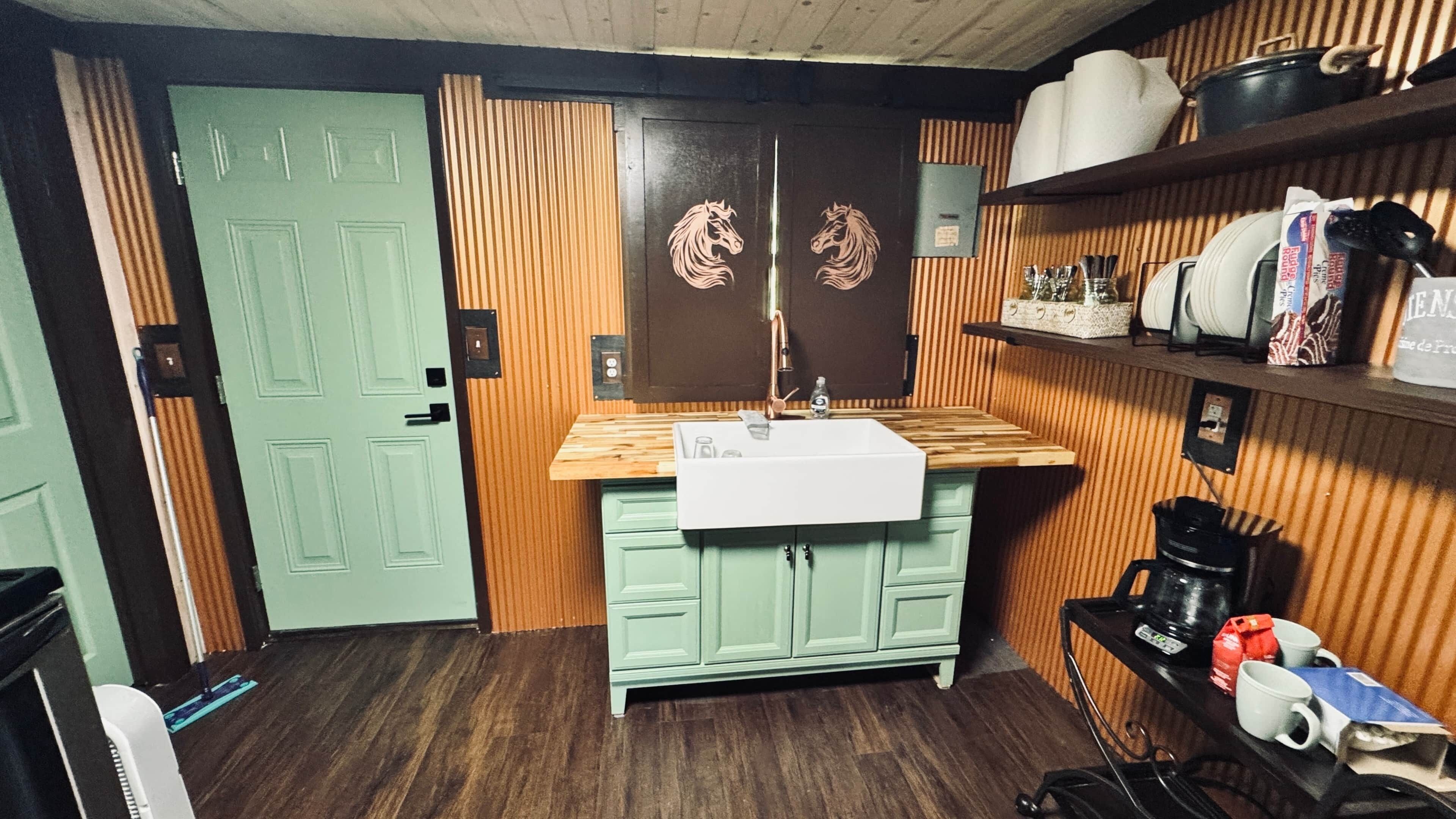 A compact kitchen with a sink, wooden countertop, and green cabinets.