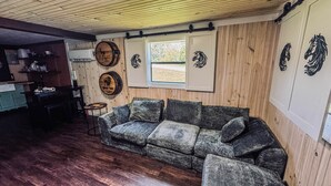 A rustic interior with a wooden ceiling, a sofa, a small table, and decorative wall art.