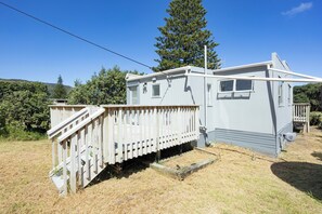 A mobile home with a wooden deck and a small porch. - OPPOSITE THE BEACH (Piha)