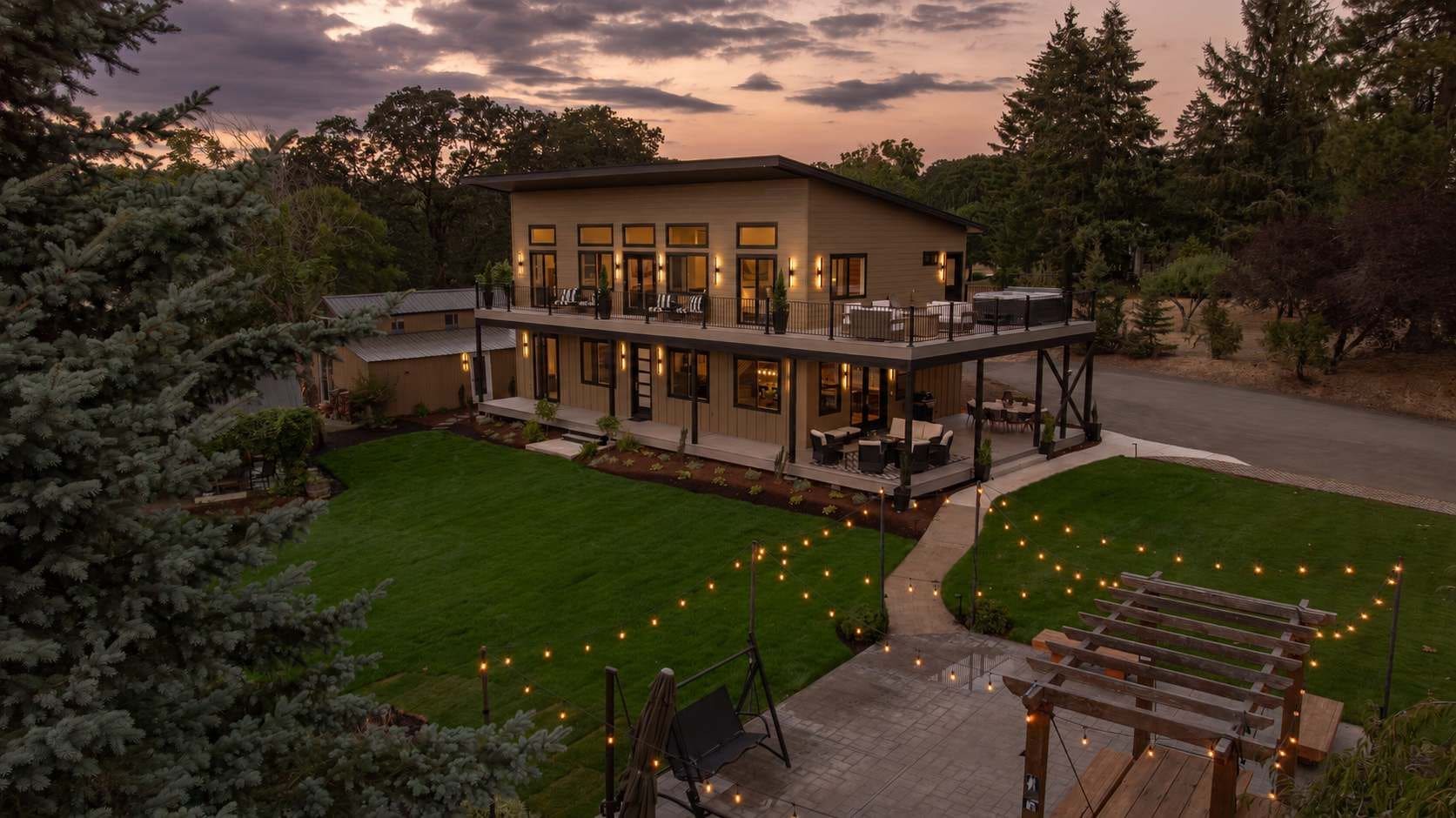 A modern two-story house with a covered patio and a well-maintained lawn.
